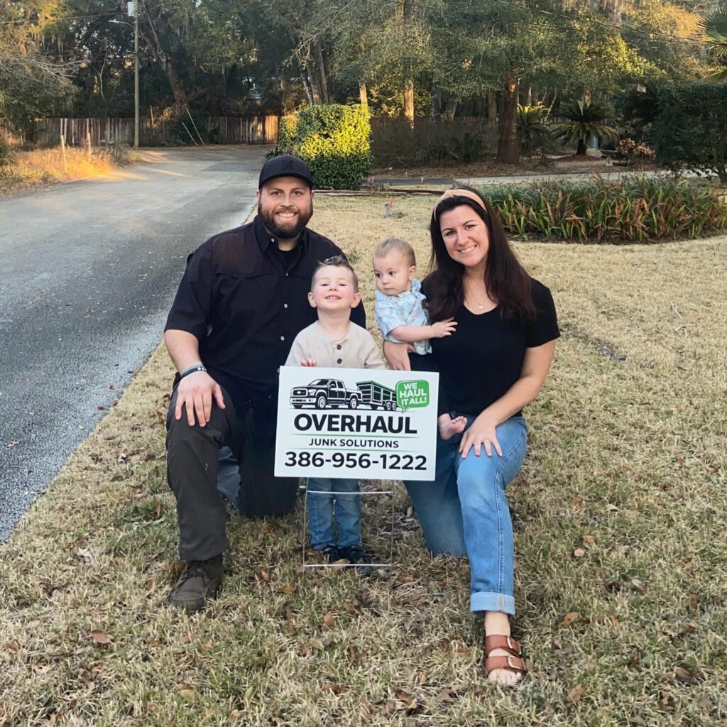 Overhaul Junk Solutions owners and family behind Yard sign promoting furniture removal, applicance removal, yard waste removal, swingset removal, trampoline removal, in the volusia county FL area