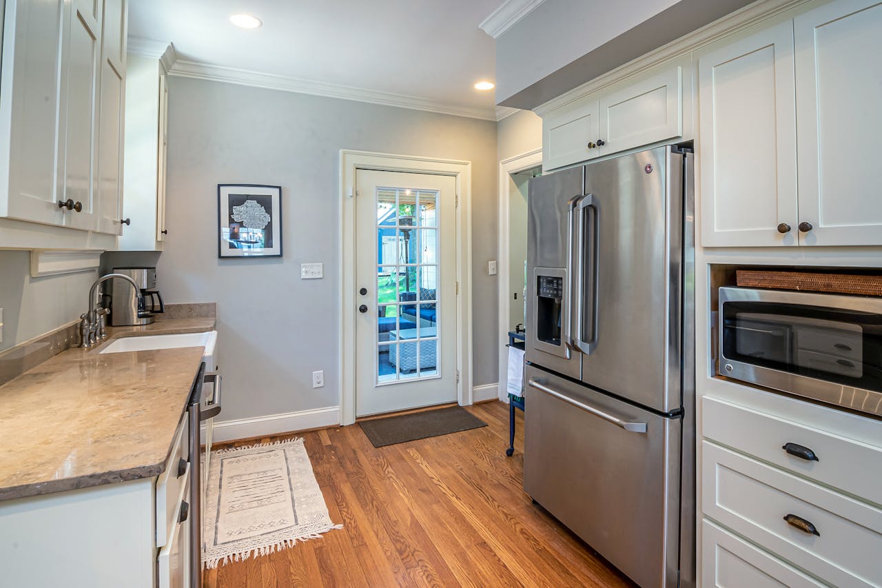 Bright kitchen with stainless steel appliances and wooden flooring.